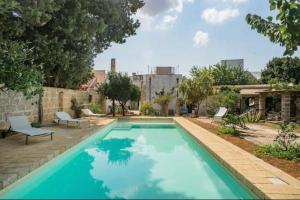 a large blue swimming pool with two chairs and a building at Villa Charita - Old Masseria in the historical town with private pool in Castrignano del Capo