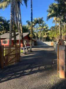 a house with palm trees and a wooden fence at Casa sitio pousada vô maneca in Timbó