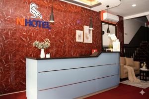 a hotel lobby with a reception counter with a red marble wall at NiHOTEL Cibaduyut Bandung in Bandung