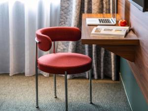une chaise rouge assise sur un bureau dans une chambre d'hôtel dans l'établissement Mercure Caen Cote De Nacre, à Caen