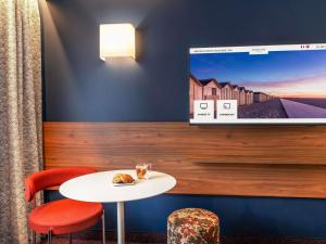 a room with a table and chairs and a tv on the wall at Mercure Caen Cote De Nacre in Caen +135 photos