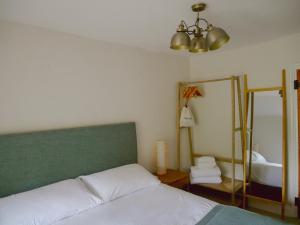 ein Schlafzimmer mit einem Bett mit grünem Kopfteil und einem Spiegel in der Unterkunft Charlotte's Cottage, a Charming Cotswolds Getaway in Adlestrop