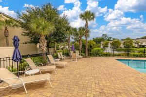 a patio with chairs and a pool with palm trees at 903 Reserve Lane in Jewtown