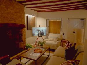 ein Wohnzimmer mit Sofa und Tisch in der Unterkunft Charlotte's Cottage, a Charming Cotswolds Getaway in Adlestrop