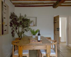 einen Esstisch mit einer Flasche Wein darauf in der Unterkunft Charlotte's Cottage, a Charming Cotswolds Getaway in Adlestrop + 19 Fotos