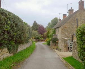 eine unbefestigte Straße in einem Dorf mit Steinhäusern in der Unterkunft Charlotte's Cottage, a Charming Cotswolds Getaway in Adlestrop