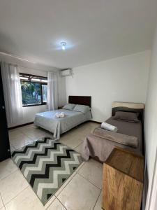 a bedroom with two beds and a rug at Casa sitio pousada vô maneca in Timbó