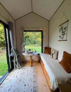 a bedroom with a bed and a table and a window at La Tiny de Mary in Gonneville-sur-Mer