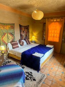a bedroom with two beds with blue sheets and a rug at Kasbah Azalay Merzouga takojt in Merzouga +43 photos