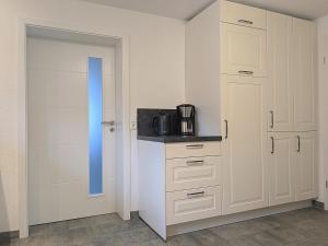 a kitchen with white cabinets and a blue door at Allgäu-Genuss in Halblech