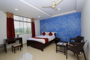 a bedroom with a bed and a blue wall at Hotel O Sri Sai Residency in Bidadi