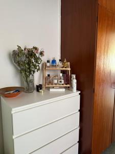 a dresser with a vase of flowers on top of it at Studio apartment in Central Copenhagen in Copenhagen +1 photo