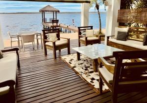 a deck with tables and chairs on the water at Villa Colosseum in Florianópolis
