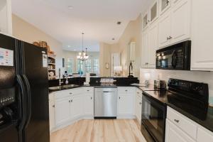Una cocina con gabinetes blancos y electrodomésticos negros. en Sand Castle, en Gulf Highlands