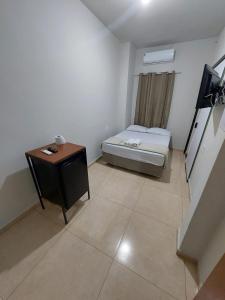 a small room with a bed and a table at Pousada Nossa Senhora de Copacabana in Aparecida