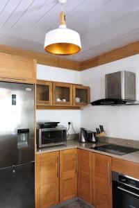 a kitchen with wooden cabinets and a stainless steel refrigerator at Cosy little House in Rodrigues Island
