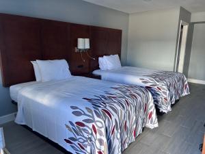 two beds sitting next to each other in a hotel room at Airport Motor Inn in Jacksonville