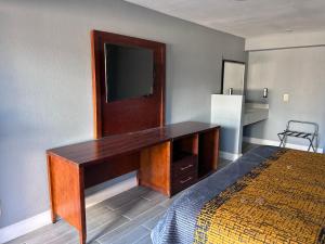 a bedroom with a desk with a television on the wall at Airport Motor Inn in Jacksonville