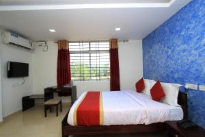 a bedroom with a bed and a desk and a window at Hotel O Sri Sai Residency in Bidadi