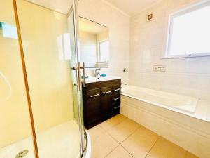 Un baño con ducha, lavabo y bañera. en Beautiful villa by the sea, en Auckland 23 fotos más