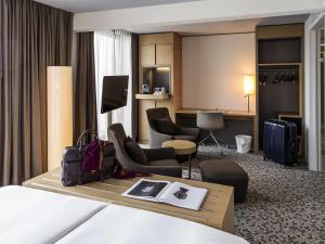 a hotel room with a bed and a desk and chairs at Pullman Basel Europe in Basel
