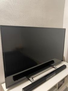 TV de pantalla plana grande en la parte superior de un estante en Studio équipé et lumineux à Plombières-lès-Dijon, proche Dijon, en Plombières-lès-Dijon
