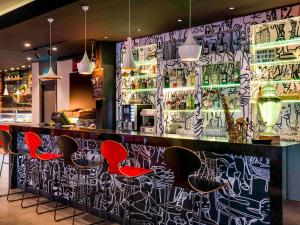 Un bar con sillas rojas y grafitis en la pared. en Ibis Istanbul Zeytinburnu, en Estambul