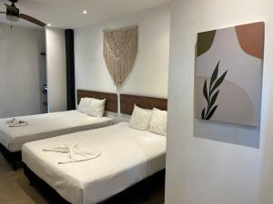 a bedroom with two beds with white sheets and a painting at Coco Live Suites in Playa del Carmen