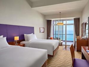 a hotel room with two beds and a view of the ocean at Novotel Nha Trang in Nha Trang