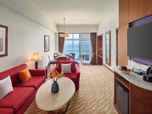 a living room with a red couch and a table at Novotel Nha Trang in Nha Trang