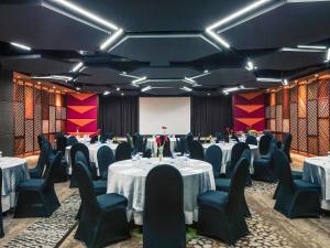 a banquet room with tables and chairs and a screen at Mercure Surabaya Grand Mirama in Surabaya +133 photos