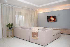 a white living room with a couch and a window at The Hide Nongoma in Nongoma