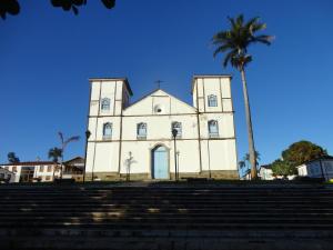 a white church with a palm tree and stairs at Pousada caminho das águas in Pirenópolis