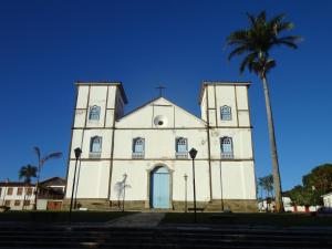 a church with a palm tree in front of it at Pousada caminho das águas in Pirenópolis