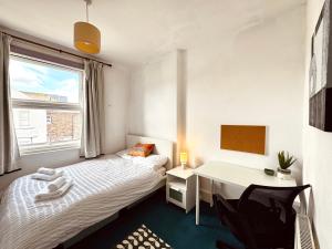 イーストボーンにある3-Bed Entire Garden Home, Walk to Beachのベッドと机と窓のある寝室