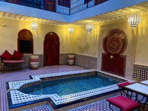 a swimming pool in a building with a table and chairs at Riad Prada in Marrakech +39 photos