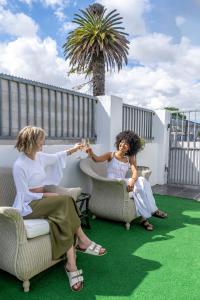 2 femmes assises sur une terrasse avec des chaises dans l'établissement Prime Executive Accommodation, au Cap