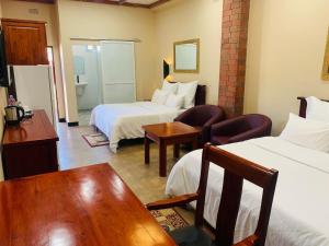 una habitación de hotel con dos camas y un sofá en Starscape Lodge, en Ndola