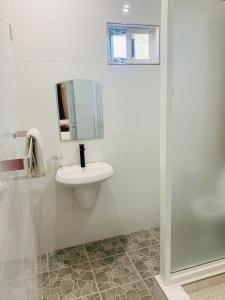 Un baño blanco con lavabo y espejo. en Starscape Lodge, en Ndola