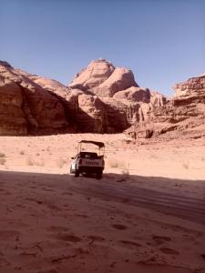 a car parked in the desert with mountains in the background at Wadi Rum Abu Khaled in Wadi Rum