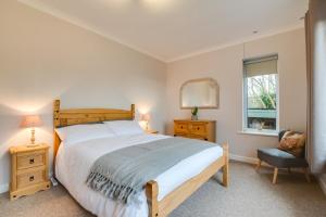 a bedroom with a bed and a chair and a window at Murmur Y Llanw in Port-Eynon