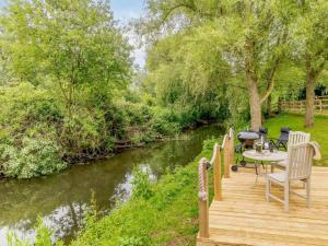 a wooden deck with a table and chairs next to a river at 1 Bed in Wool 88099 in Wool