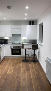a kitchen with white cabinets and a table and two stools at Posh 1 Bed Property Close to Lakeside Shopping Centre- Direct Links to London in West Thurrock