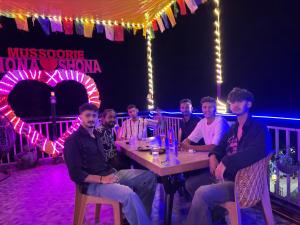 a group of men sitting at a table in front of a stage at Nona shona chill point homestay and cafe in Mussoorie +23 photos