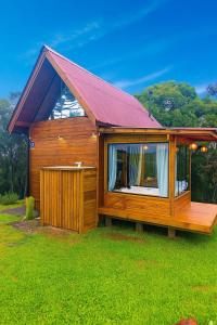 a wooden cabin with a red roof on the grass at Chalé na Pousada Eco das Aves próximo a vinícola Thera in Bom Retiro
