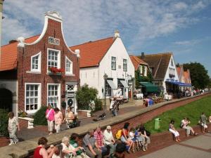 een groep mensen die op een muur in een stad zitten bij Suurhusen - Greetsiel in Greetsiel