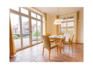 een eetkamer met een tafel, stoelen en ramen bij Suurhusen - Greetsiel in Greetsiel