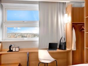 a bedroom with a desk with a laptop and a window at ibis Brighton City Centre - Station in Brighton & Hove