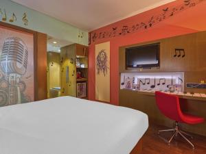 a bedroom with a white bed and a red chair at Novotel Bengaluru Outer Ring Road in Bangalore