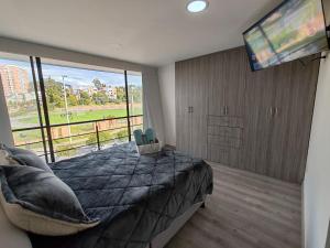 a bedroom with a large bed and a flat screen tv at Apartamento moderno frente a la Universidad Santo Tomás WiFi y parqueadero in Tunja
